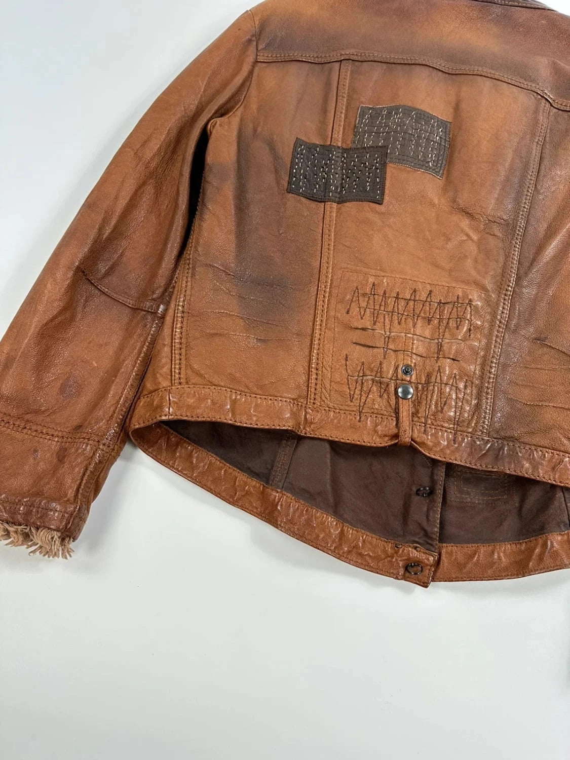 Marithé Francois Girbaud brown leather jacket with orange patches and logo details.