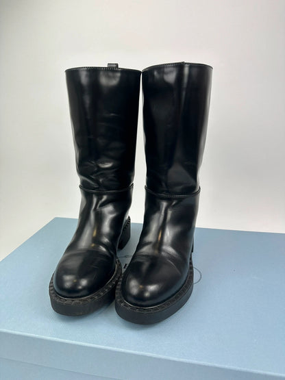 Prada black knee-high boots in patent leather with logo detail and elegant design.
