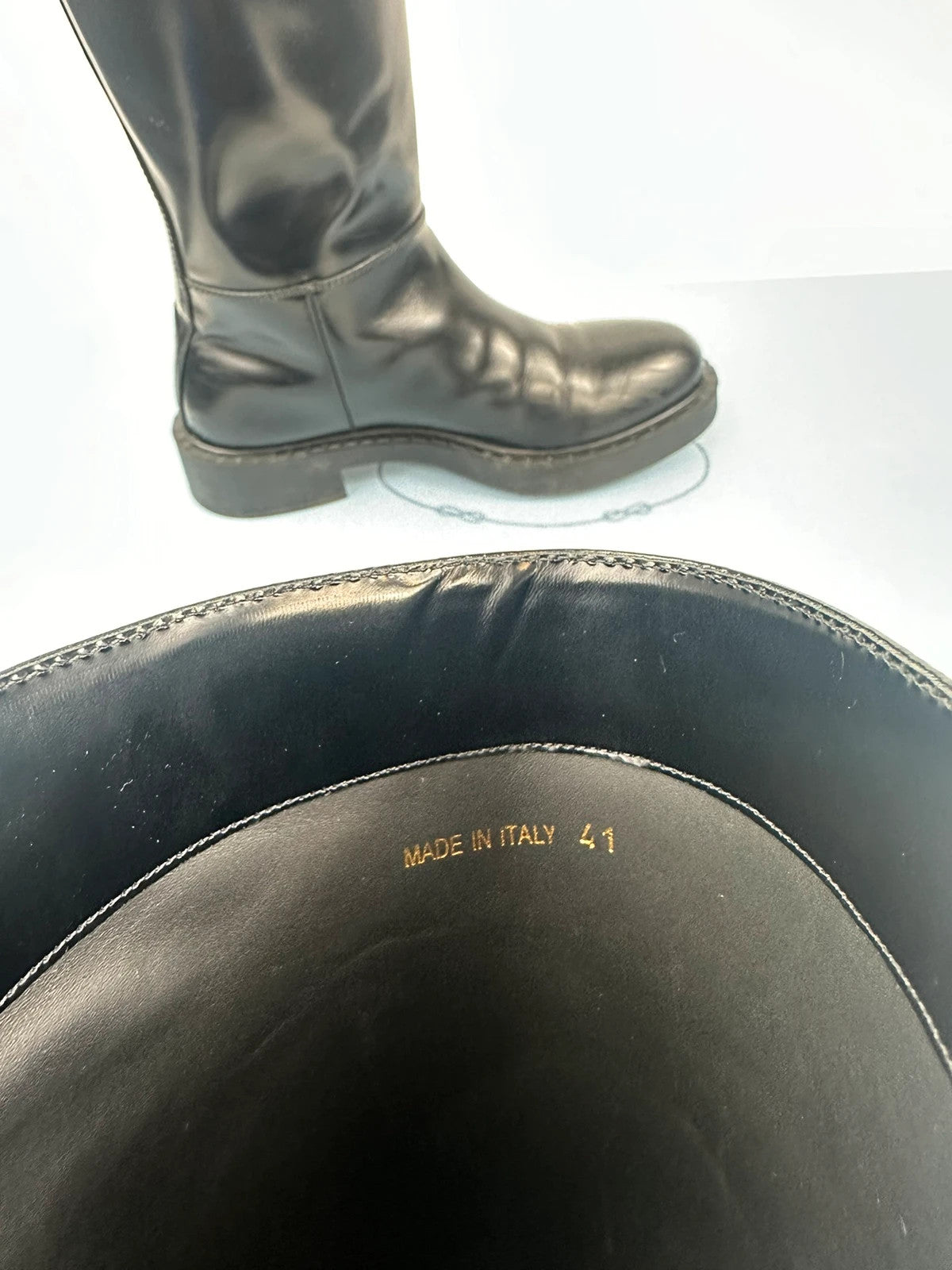 Prada black knee-high boots in patent leather with logo detail and elegant design.