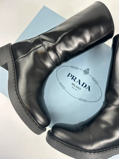 Prada black knee-high boots in patent leather with logo detail and elegant design.