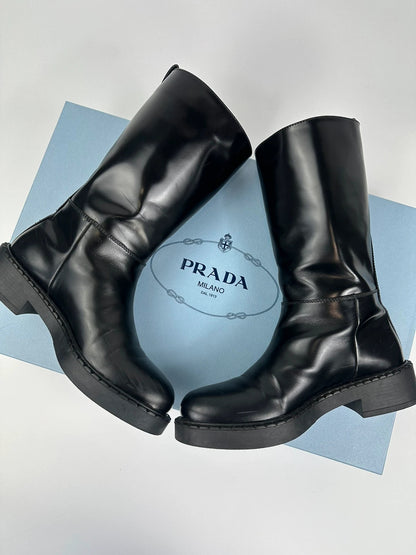 Prada black knee-high boots in patent leather with logo detail and elegant design.