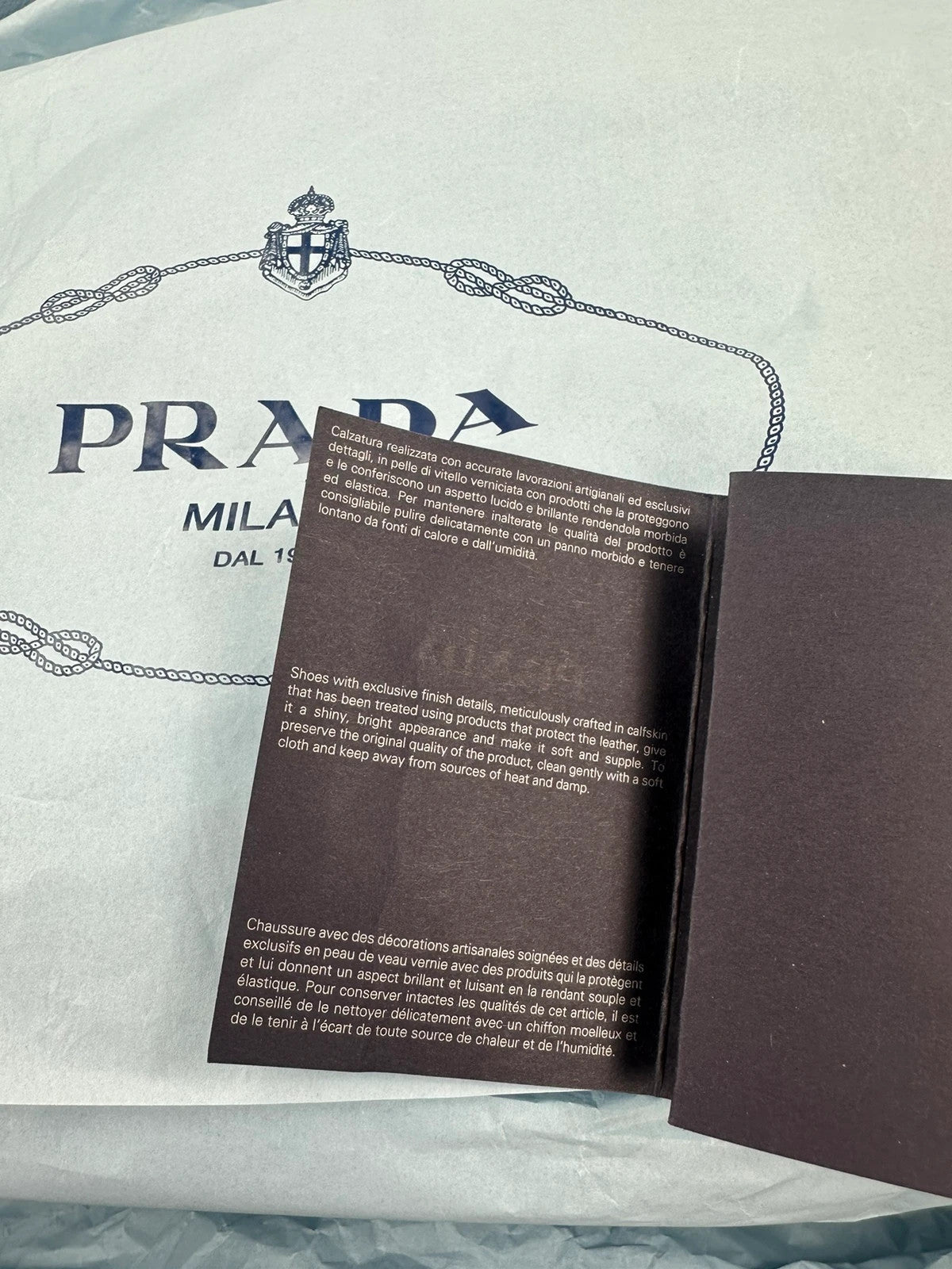 Prada black knee-high boots in patent leather with logo detail and elegant design.
