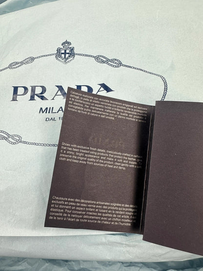 Prada black knee-high boots in patent leather with logo detail and elegant design.