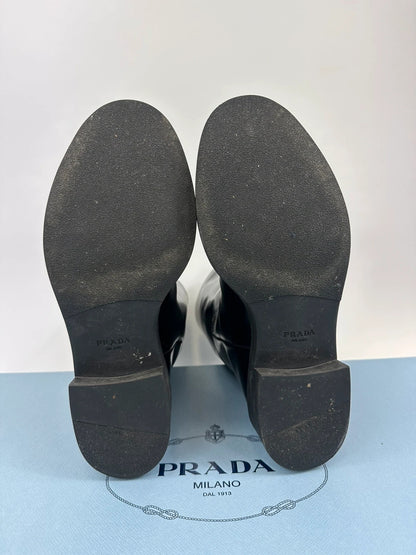 Prada black knee-high boots in patent leather with logo detail and elegant design.