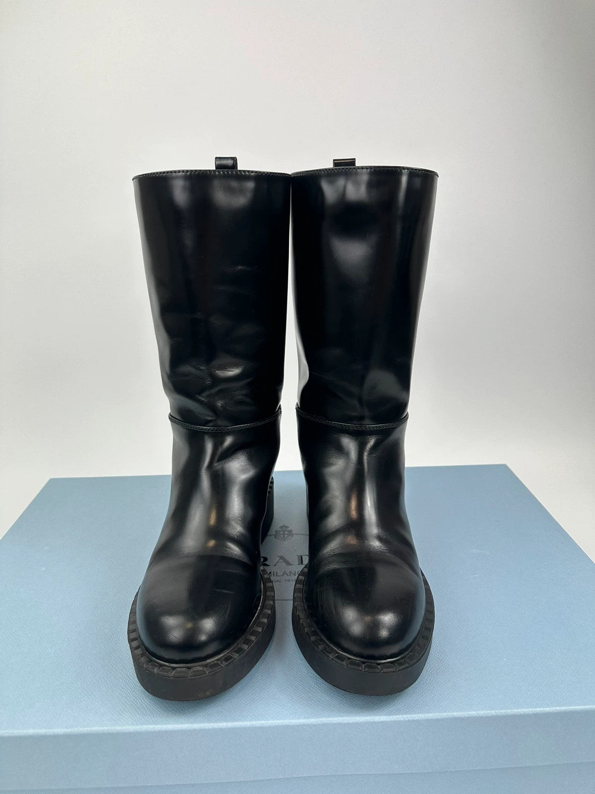 Prada black knee-high boots in patent leather with logo detail and elegant design.