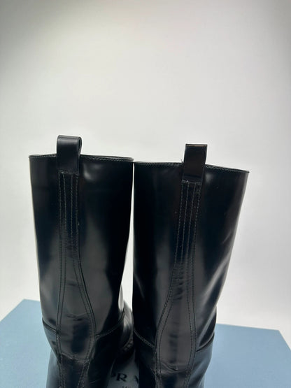 Prada black knee-high boots in patent leather with logo detail and elegant design.