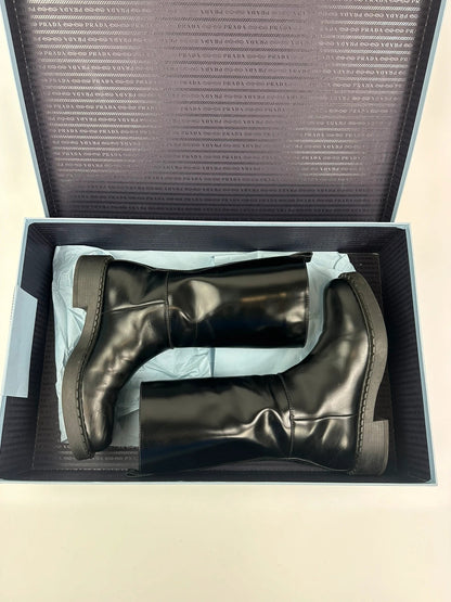Prada black knee-high boots in patent leather with logo detail and elegant design.