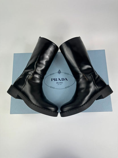 Prada black knee-high boots in patent leather with logo detail and elegant design.