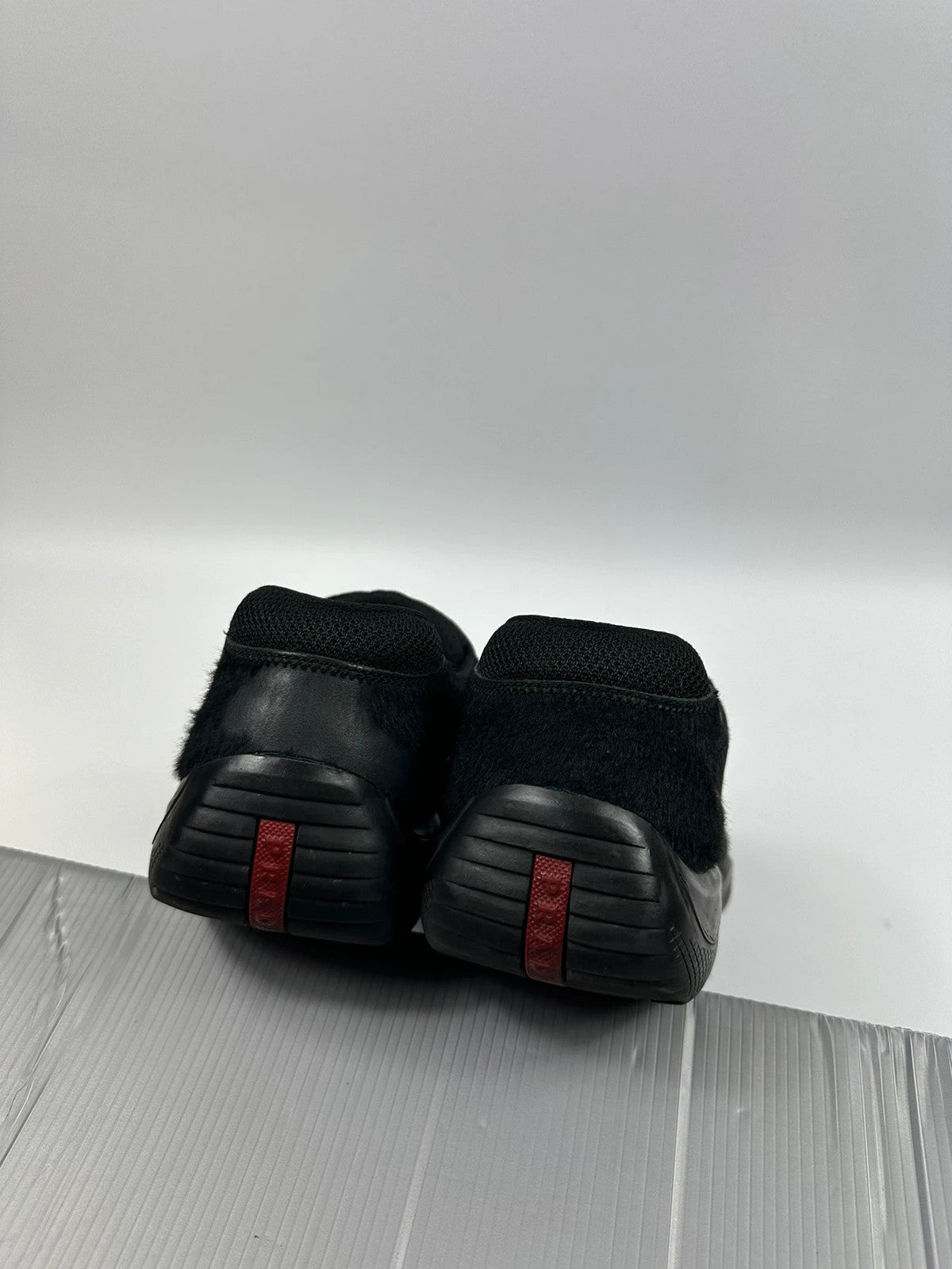 Prada black trainers with fur accents and mesh detailing, includes authenticity card.