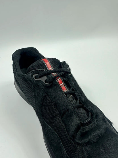 Prada black trainers with fur accents and mesh detailing, includes authenticity card.