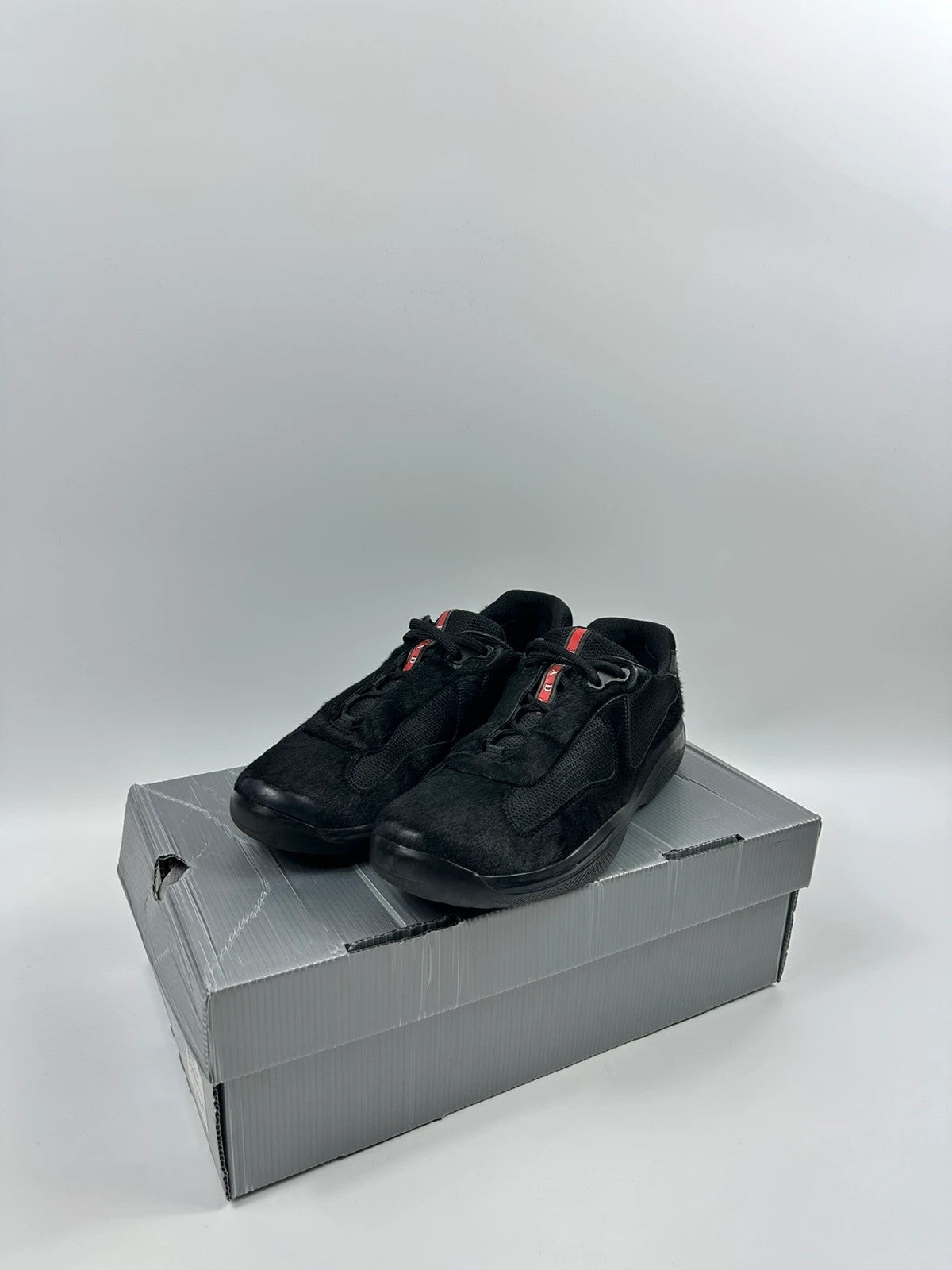 Prada black trainers with fur accents and mesh detailing, includes authenticity card.