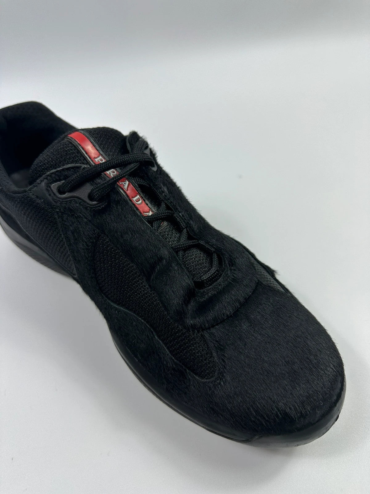Prada black trainers with fur accents and mesh detailing, includes authenticity card.