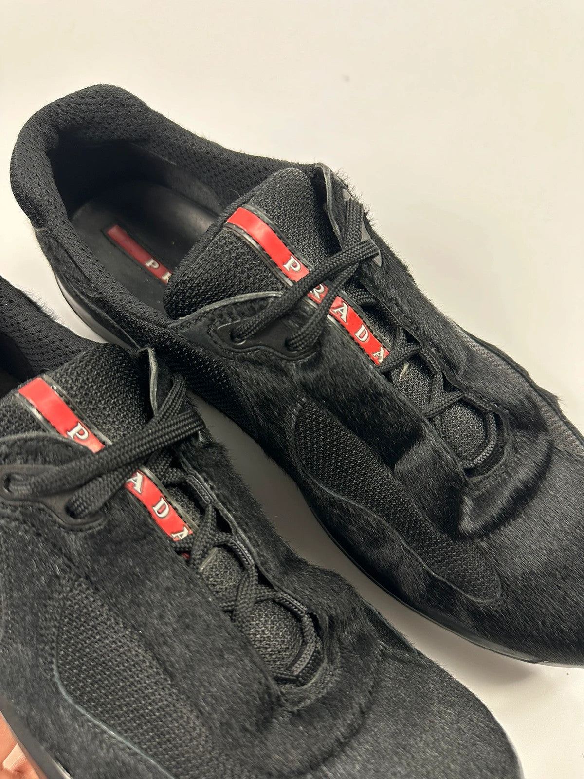 Prada black trainers with fur accents and mesh detailing, includes authenticity card.