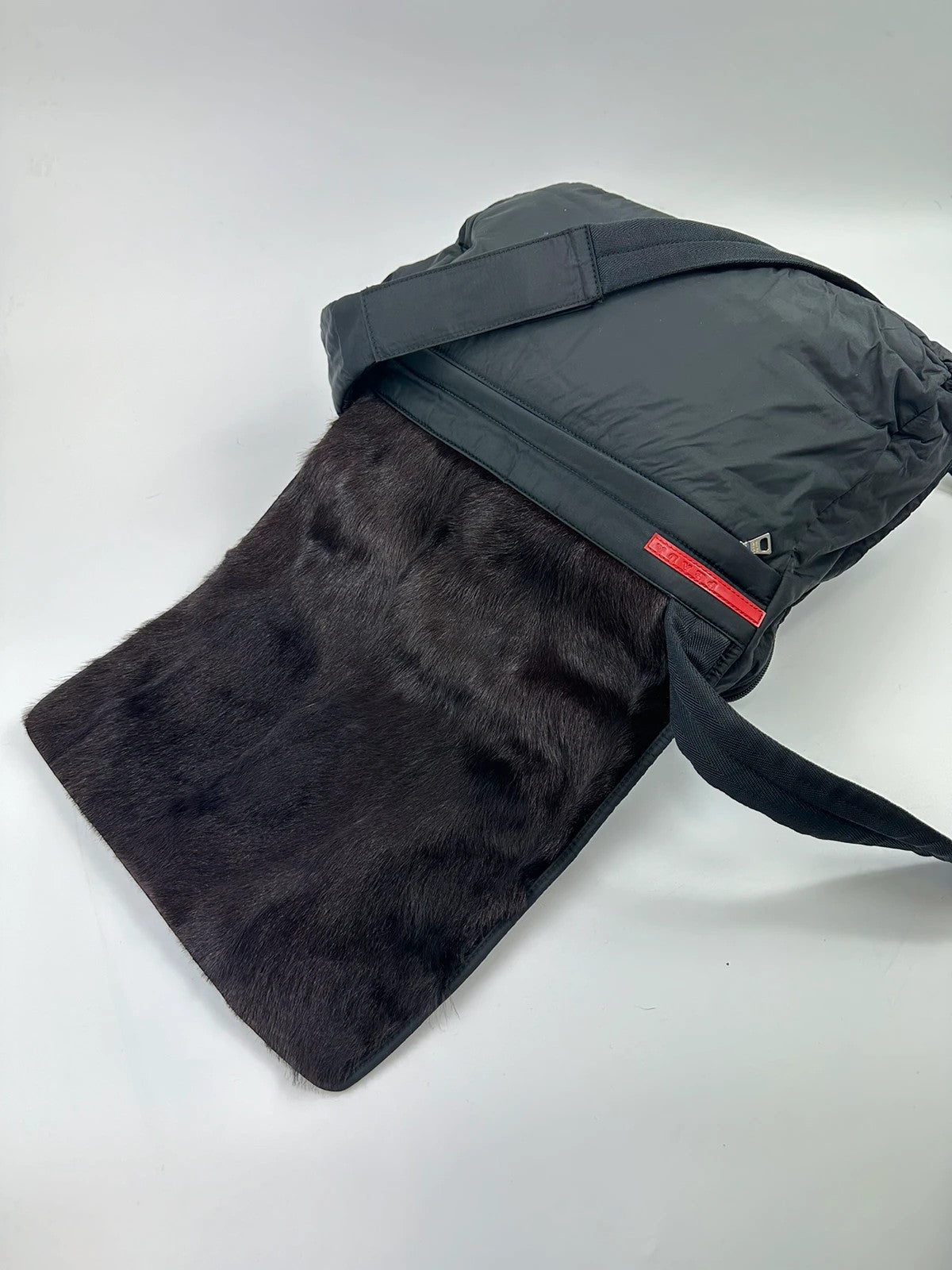 Prada black nylon crossbody bag with fur accents and linearossa logo.