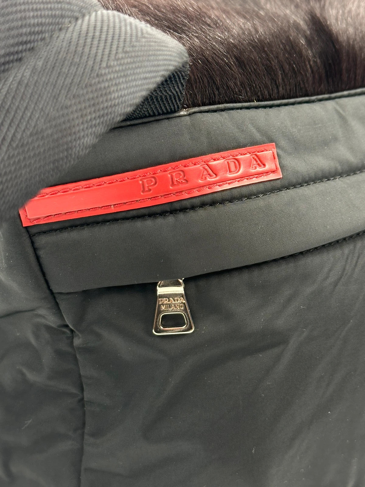 Prada black nylon crossbody bag with fur accents and linearossa logo.