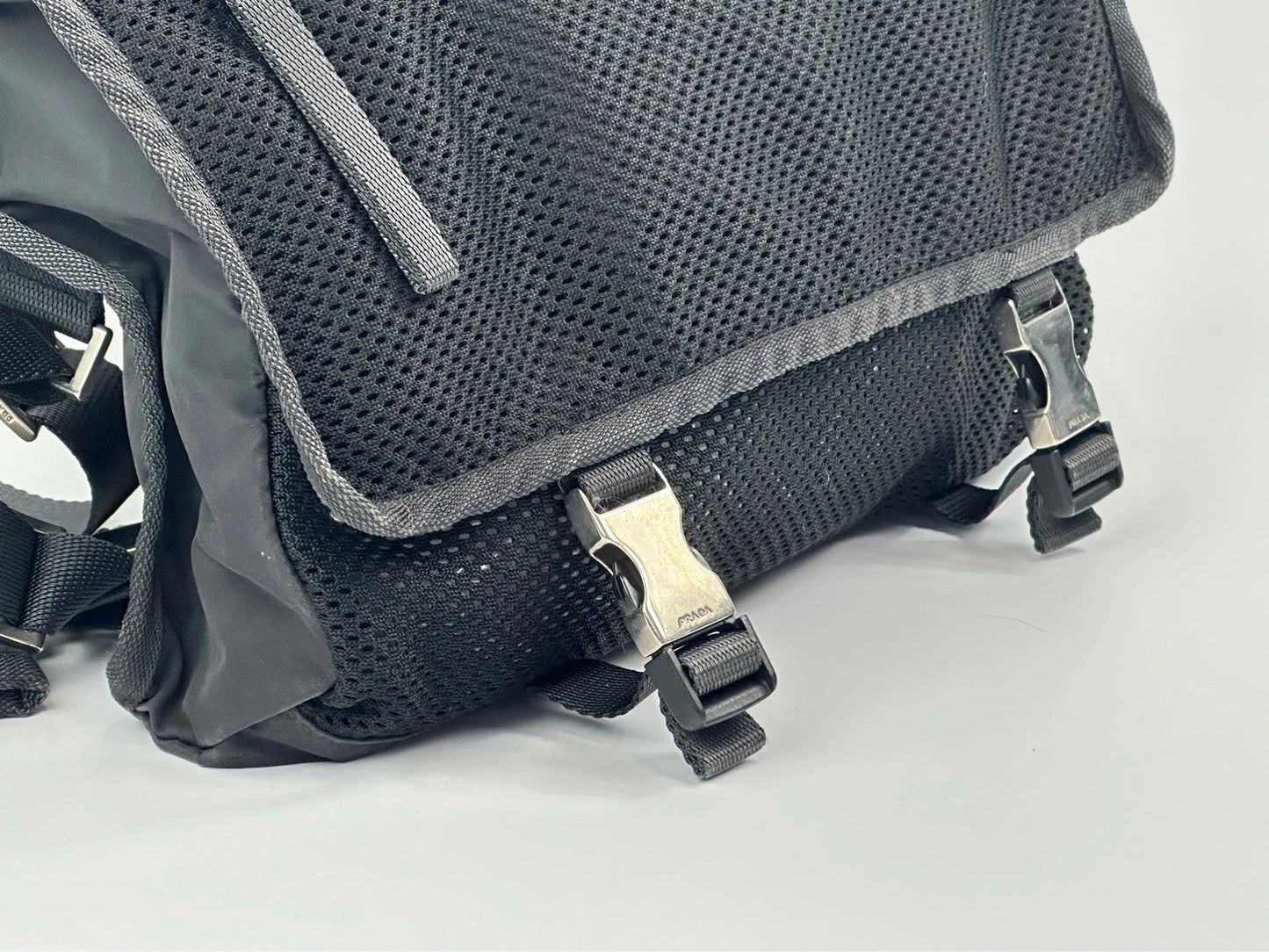 Prada black and grey mesh crossbody waist bag with logo and dual compartment design.