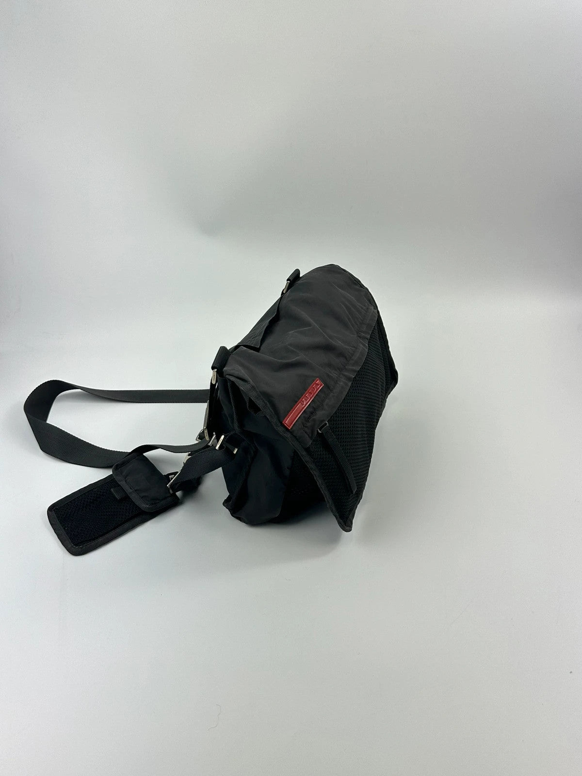Prada black and grey mesh crossbody waist bag with logo and dual compartment design.