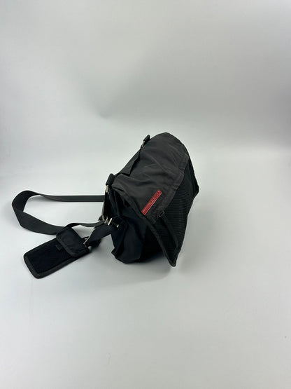 Prada black and grey mesh crossbody waist bag with logo and dual compartment design.