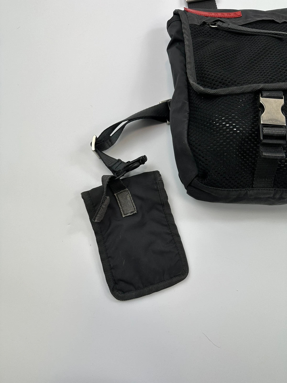 Prada black and grey mesh crossbody waist bag with logo and dual compartment design.