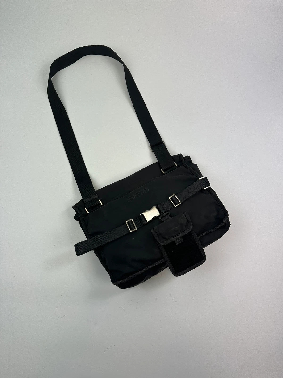 Prada black and grey mesh crossbody waist bag with logo and dual compartment design.