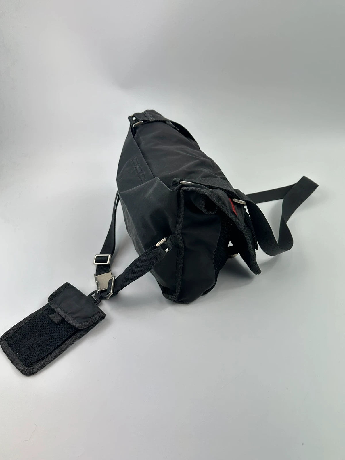 Prada black and grey mesh crossbody waist bag with logo and dual compartment design.