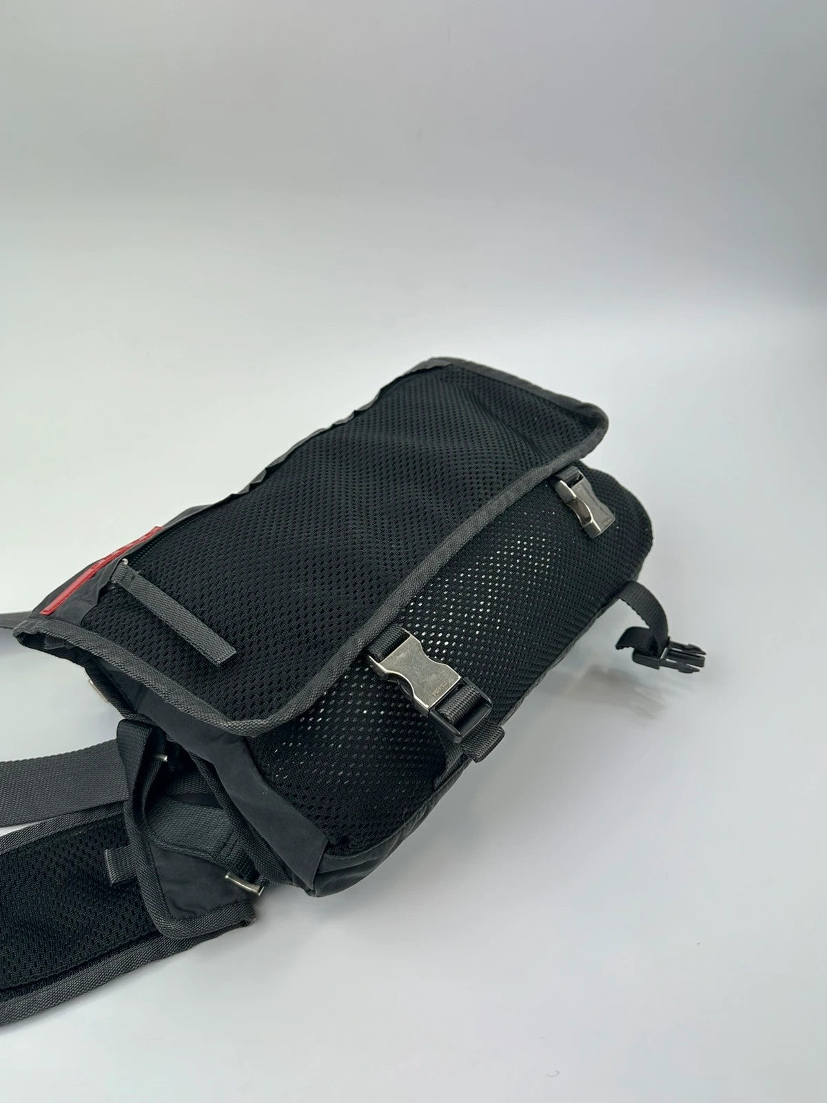 Prada black and grey mesh crossbody waist bag with logo and dual compartment design.