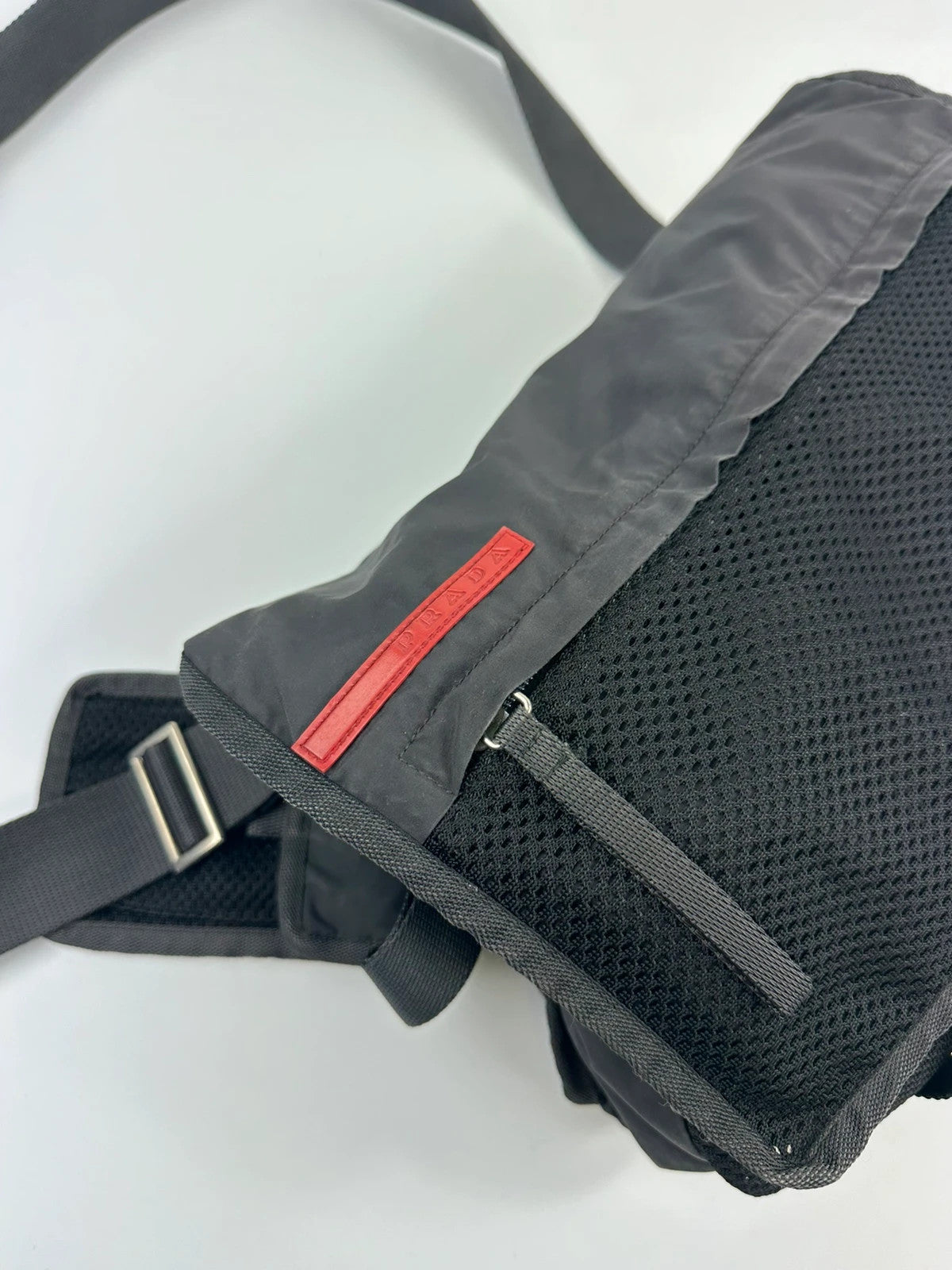 Prada black and grey mesh crossbody waist bag with logo and dual compartment design.