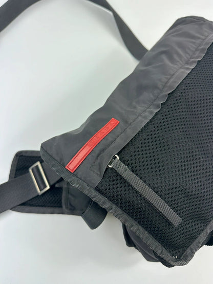 Prada black and grey mesh crossbody waist bag with logo and dual compartment design.