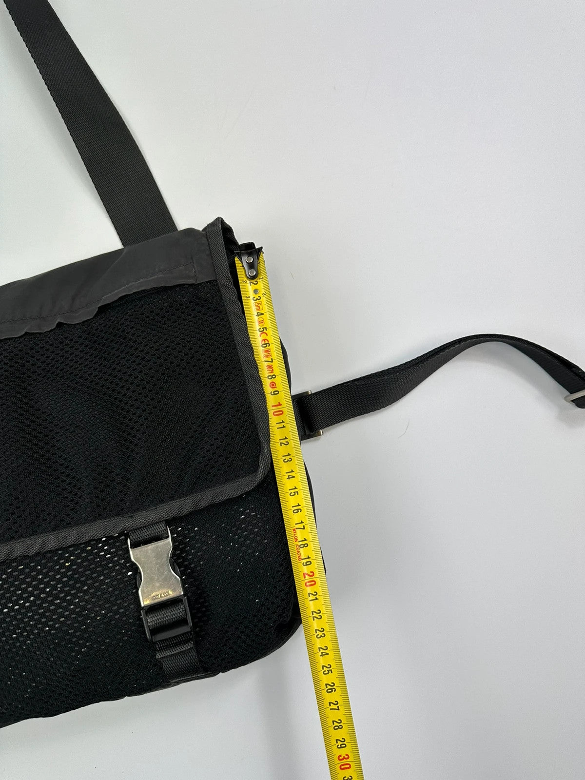 Prada black and grey mesh crossbody waist bag with logo and dual compartment design.