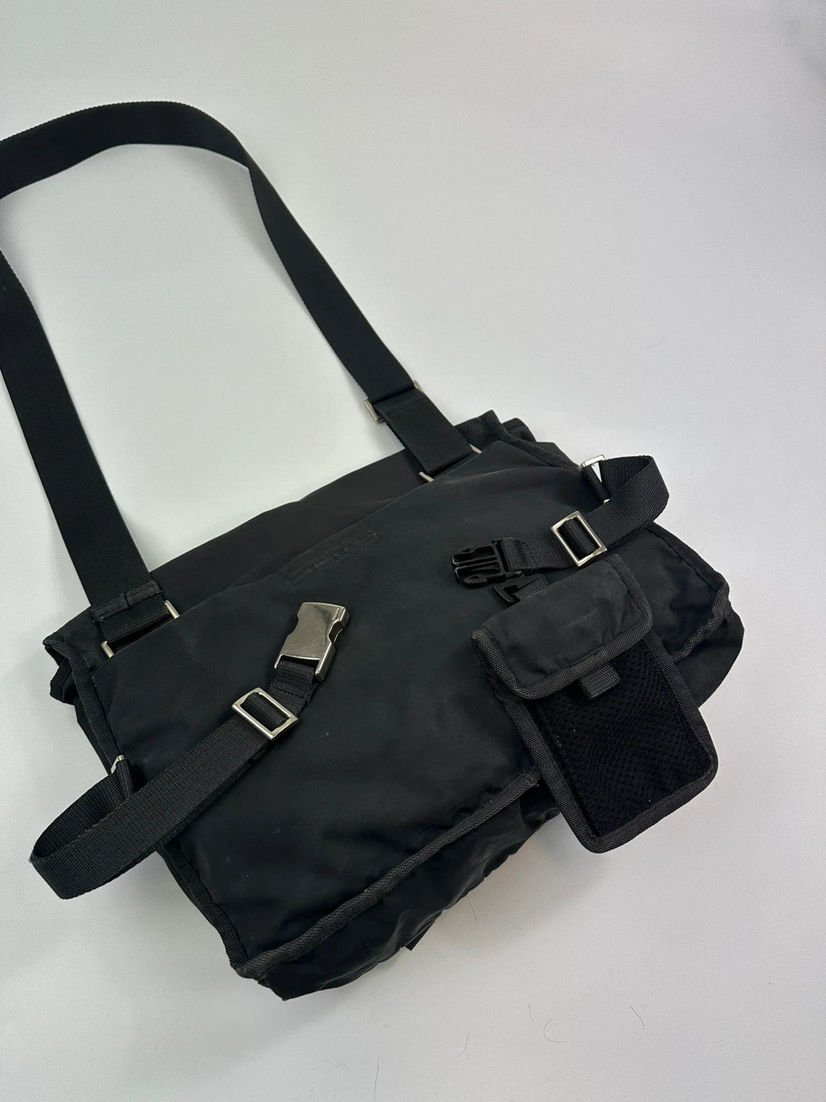 Prada black and grey mesh crossbody waist bag with logo and dual compartment design.