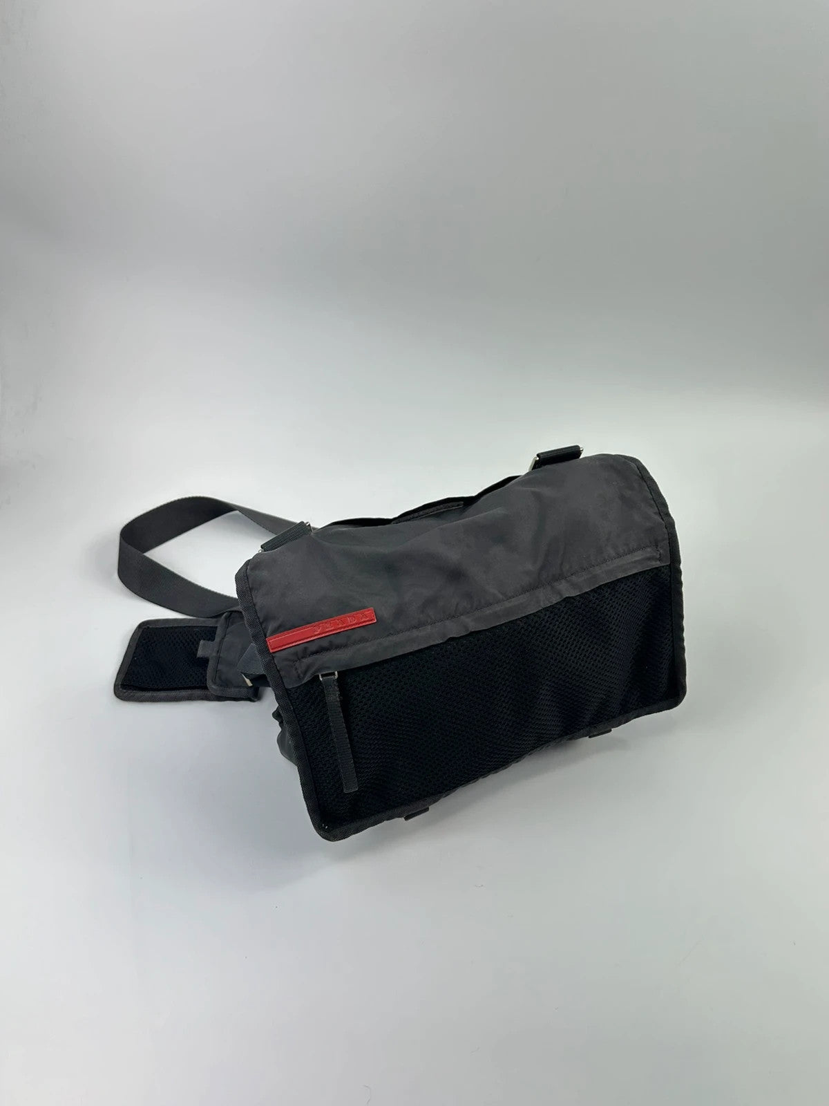 Prada black and grey mesh crossbody waist bag with logo and dual compartment design.