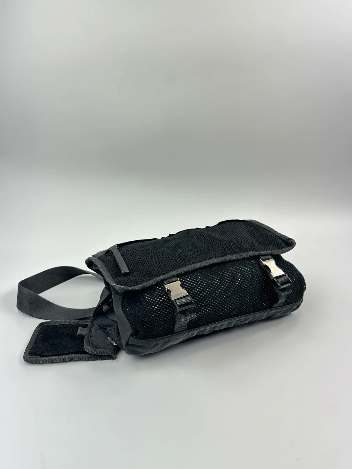 Prada black and grey mesh crossbody waist bag with logo and dual compartment design.