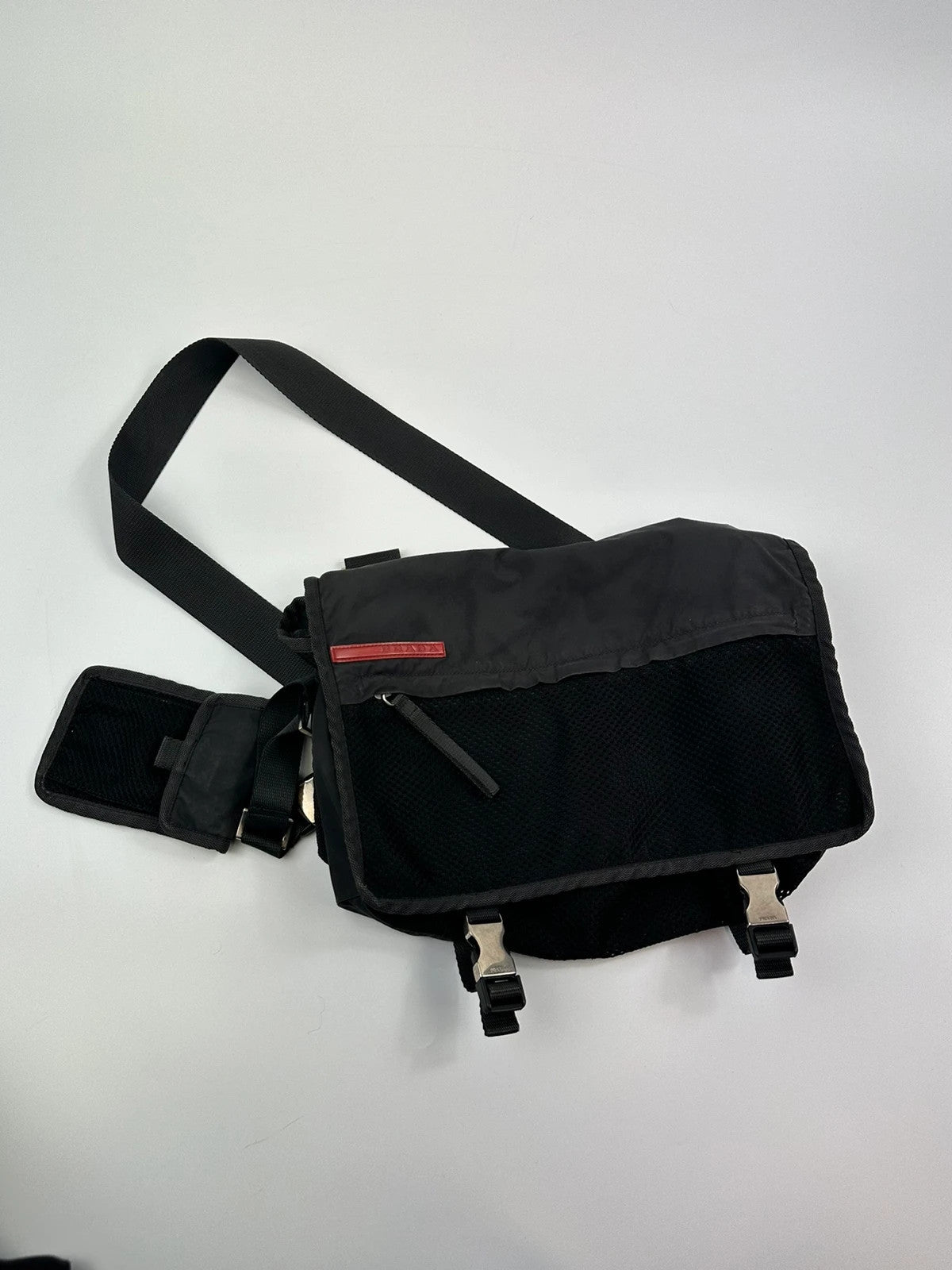 Prada black and grey mesh crossbody waist bag with logo and dual compartment design.