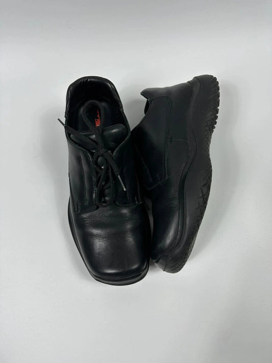 Prada black leather loafer with Vibram sole, sleek futuristic design from FW1999 collection.