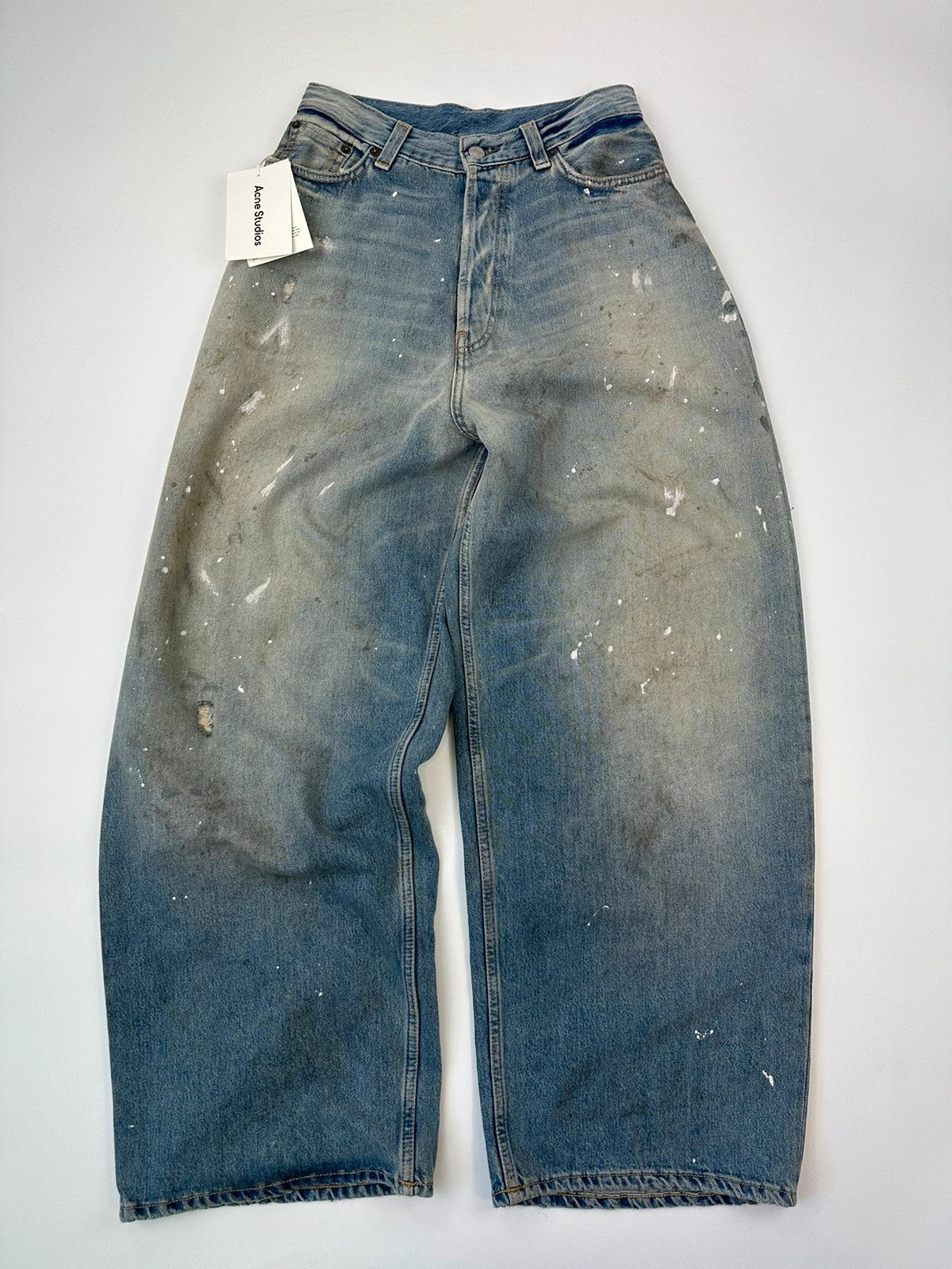 Acne Studios blue and white baggy jeans with intentional paint splatters and non-stretch denim.