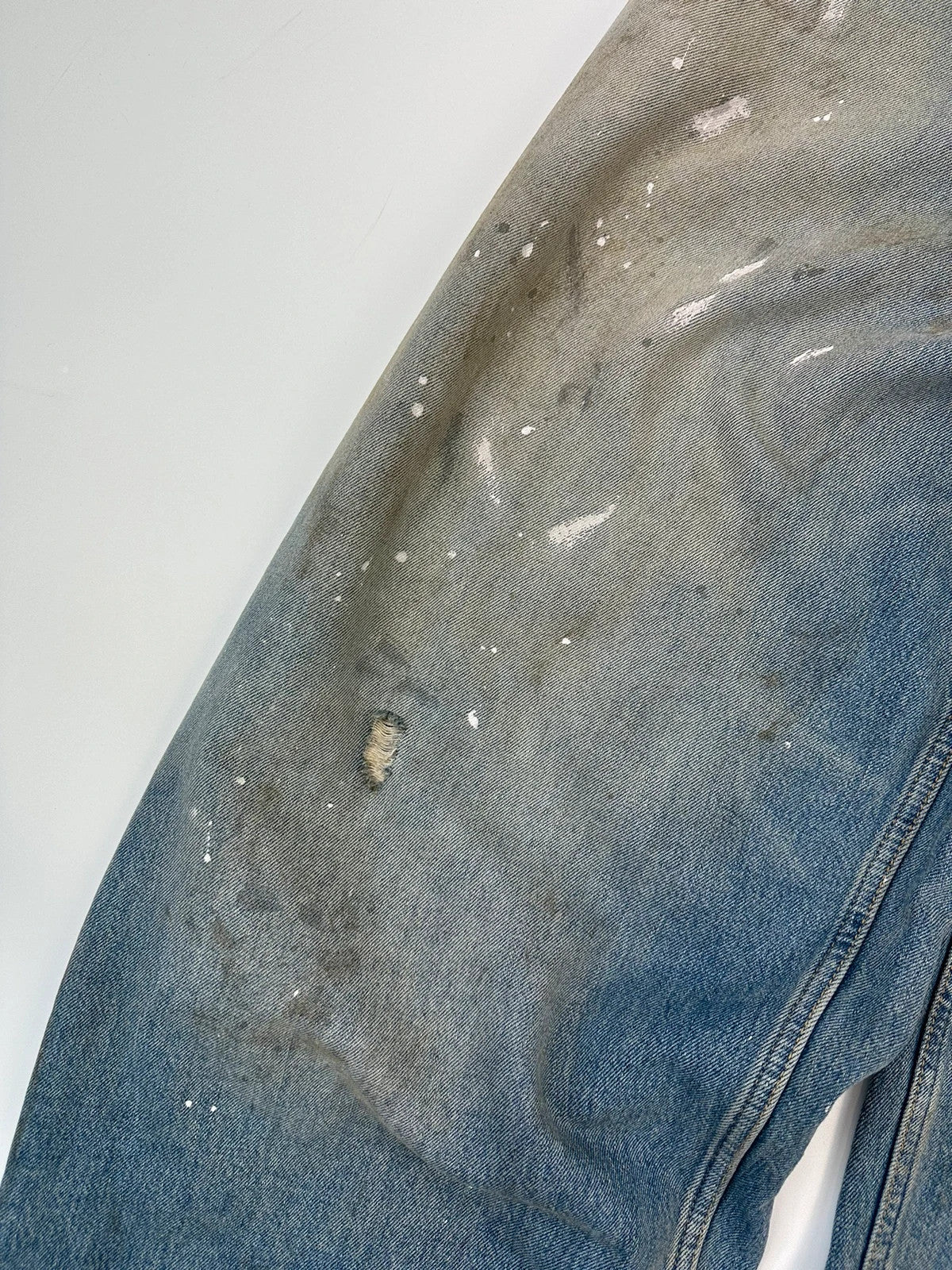 Acne Studios blue and white baggy jeans with intentional paint splatters and non-stretch denim.