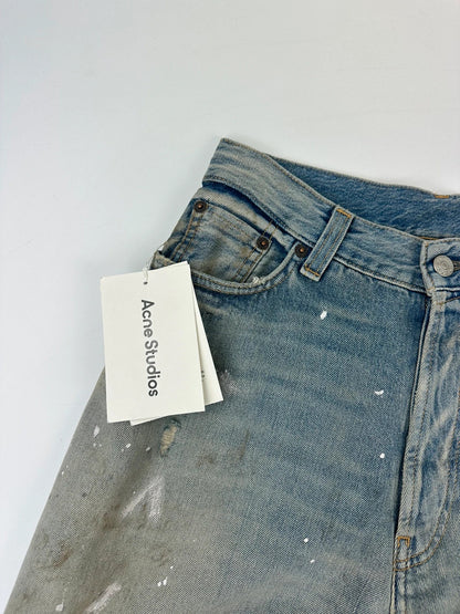 Acne Studios blue and white baggy jeans with intentional paint splatters and non-stretch denim.