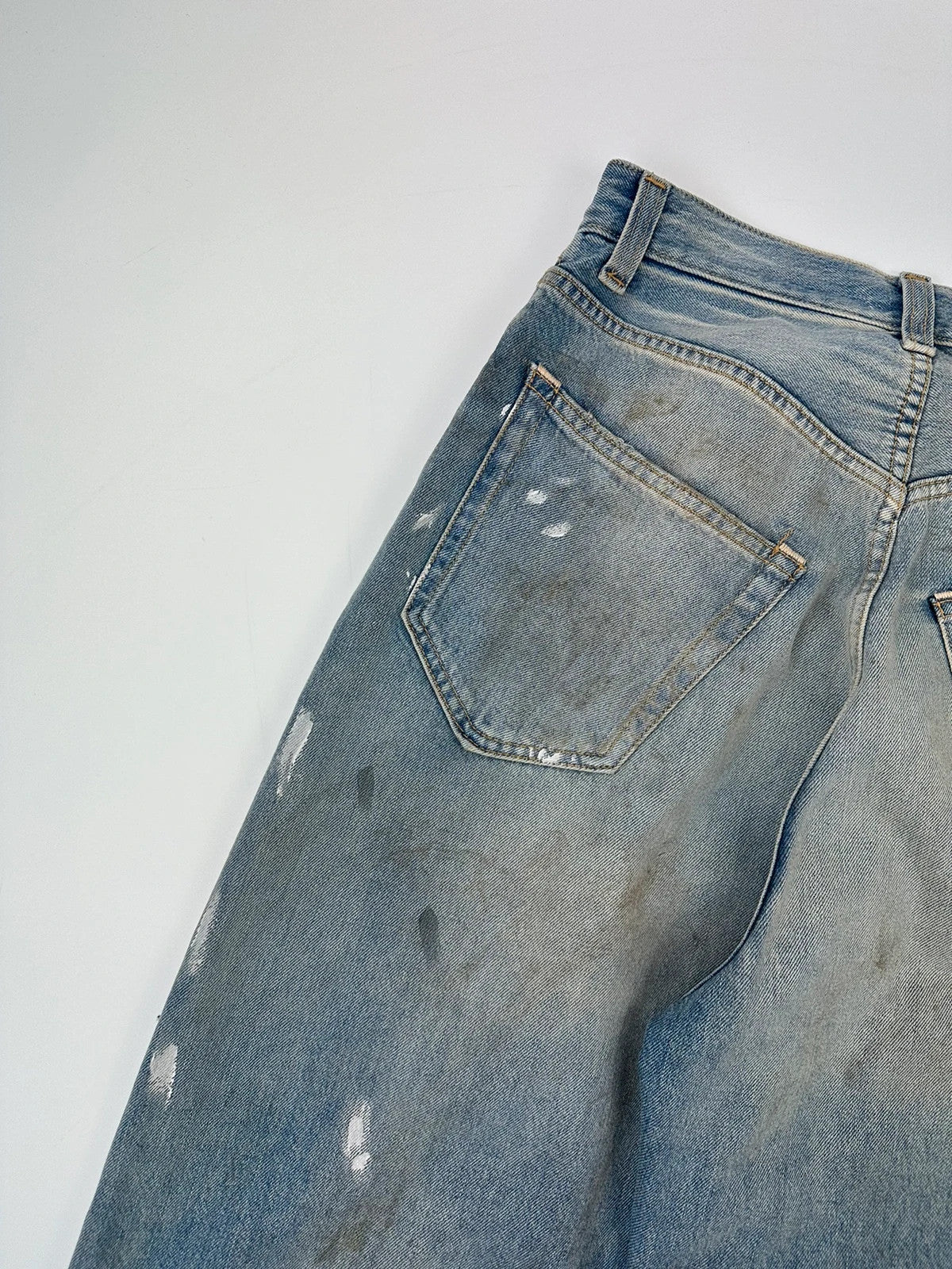Acne Studios blue and white baggy jeans with intentional paint splatters and non-stretch denim.