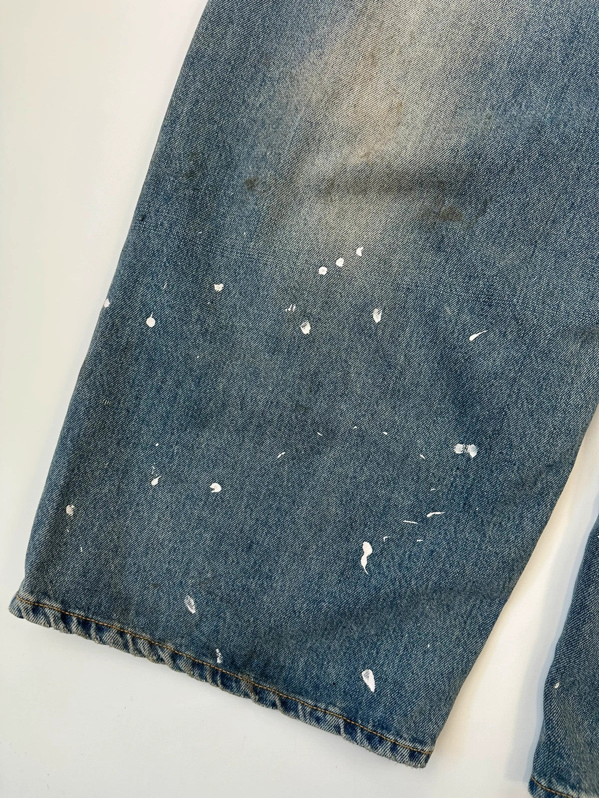 Acne Studios blue and white baggy jeans with intentional paint splatters and non-stretch denim.
