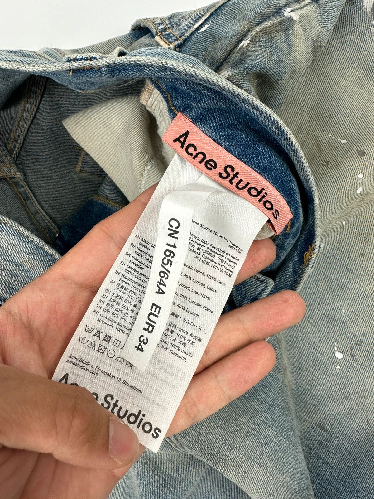 Acne Studios blue and white baggy jeans with intentional paint splatters and non-stretch denim.