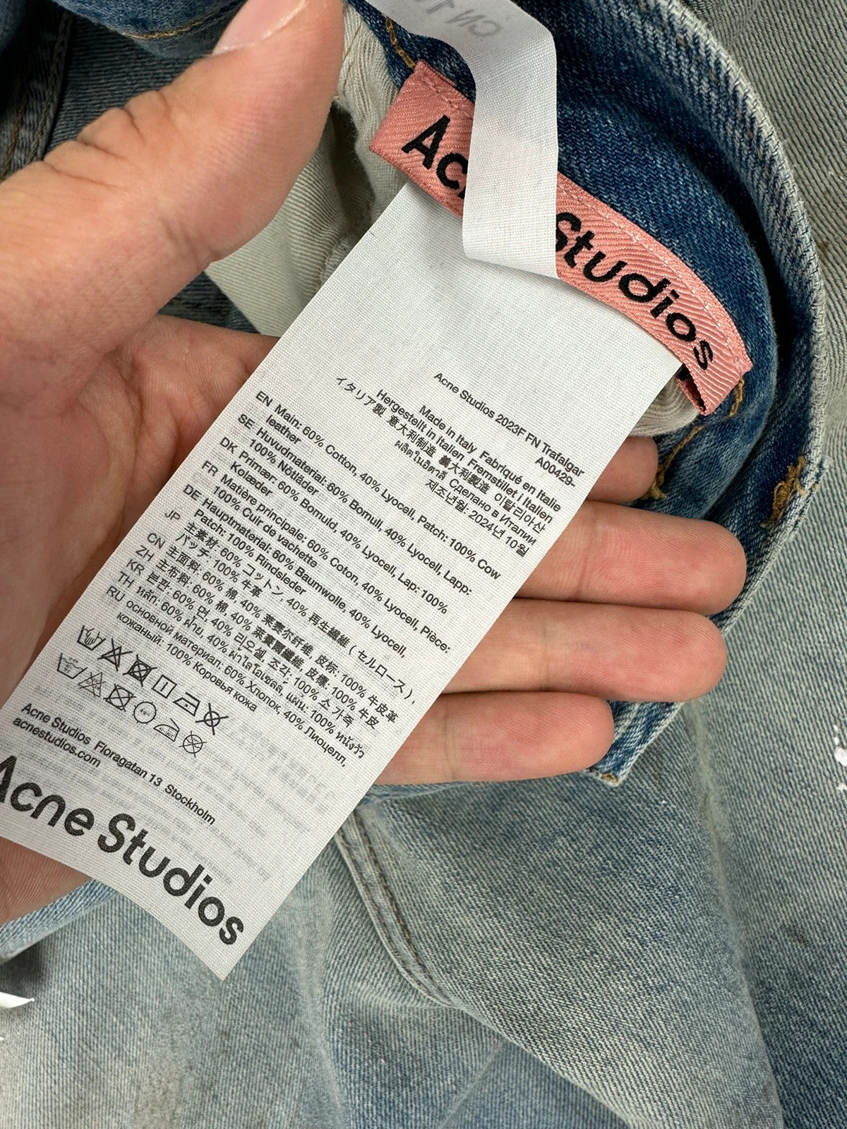 Acne Studios blue and white baggy jeans with intentional paint splatters and non-stretch denim.
