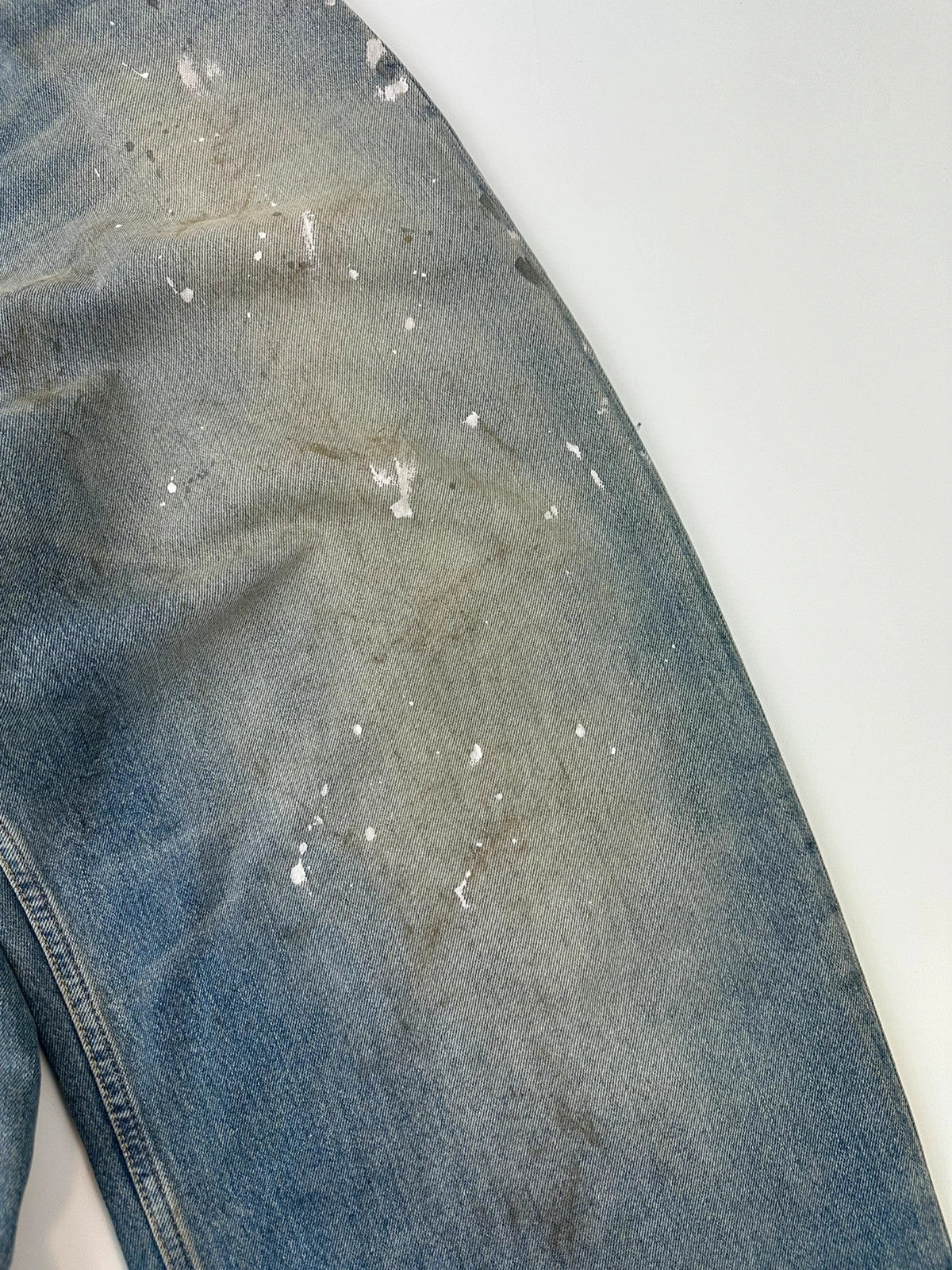 Acne Studios blue and white baggy jeans with intentional paint splatters and non-stretch denim.