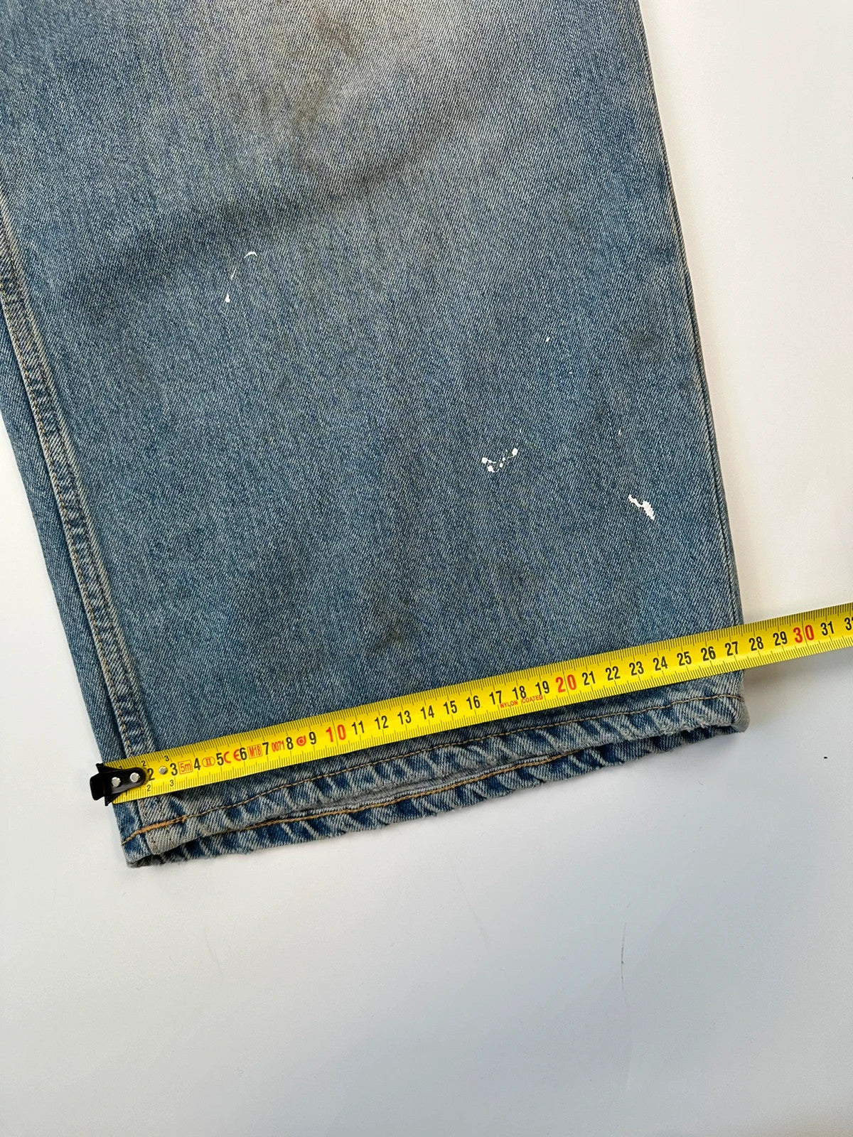 Acne Studios blue and white baggy jeans with intentional paint splatters and non-stretch denim.