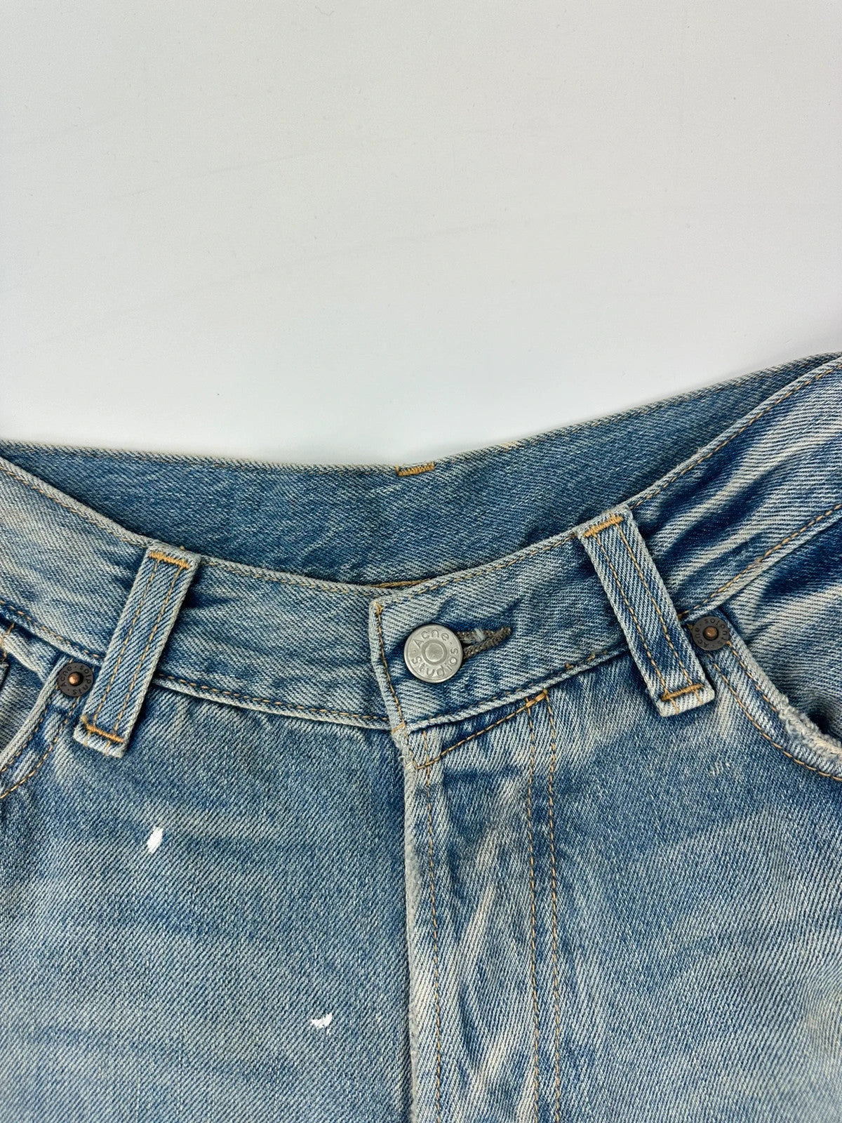 Acne Studios blue and white baggy jeans with intentional paint splatters and non-stretch denim.