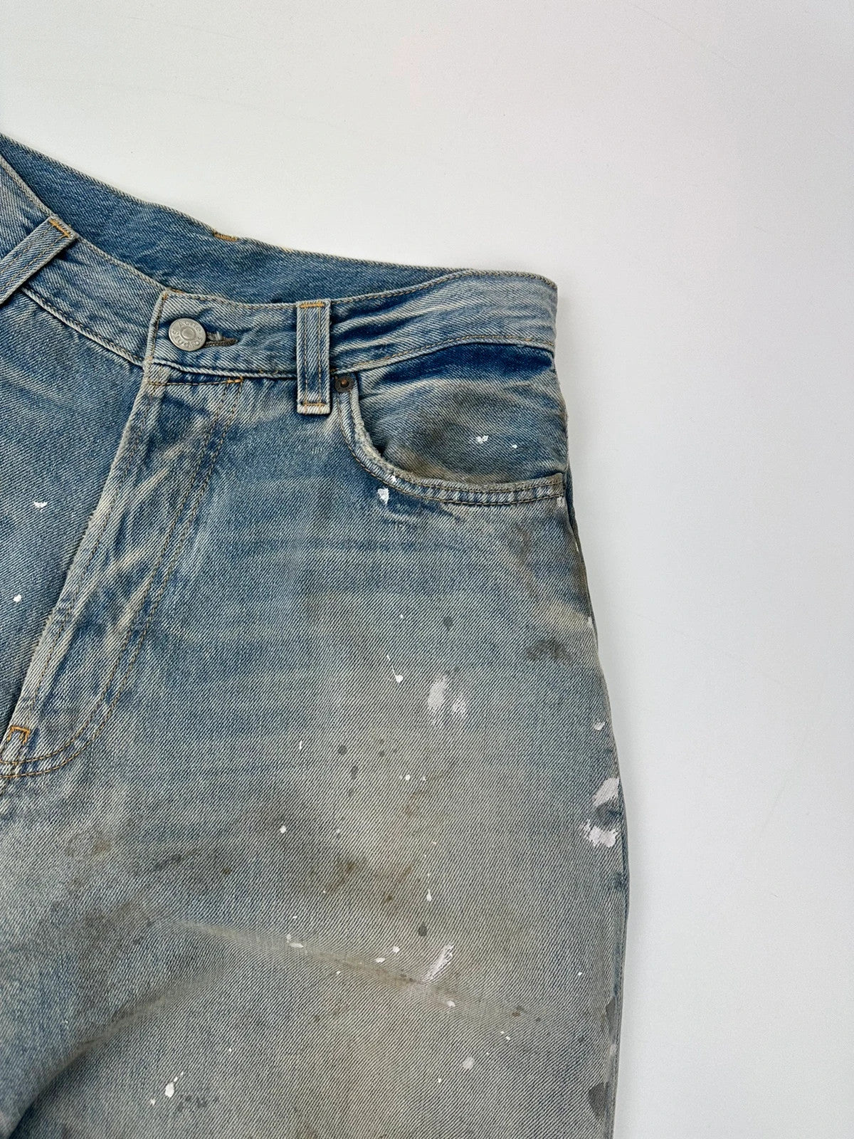Acne Studios blue and white baggy jeans with intentional paint splatters and non-stretch denim.