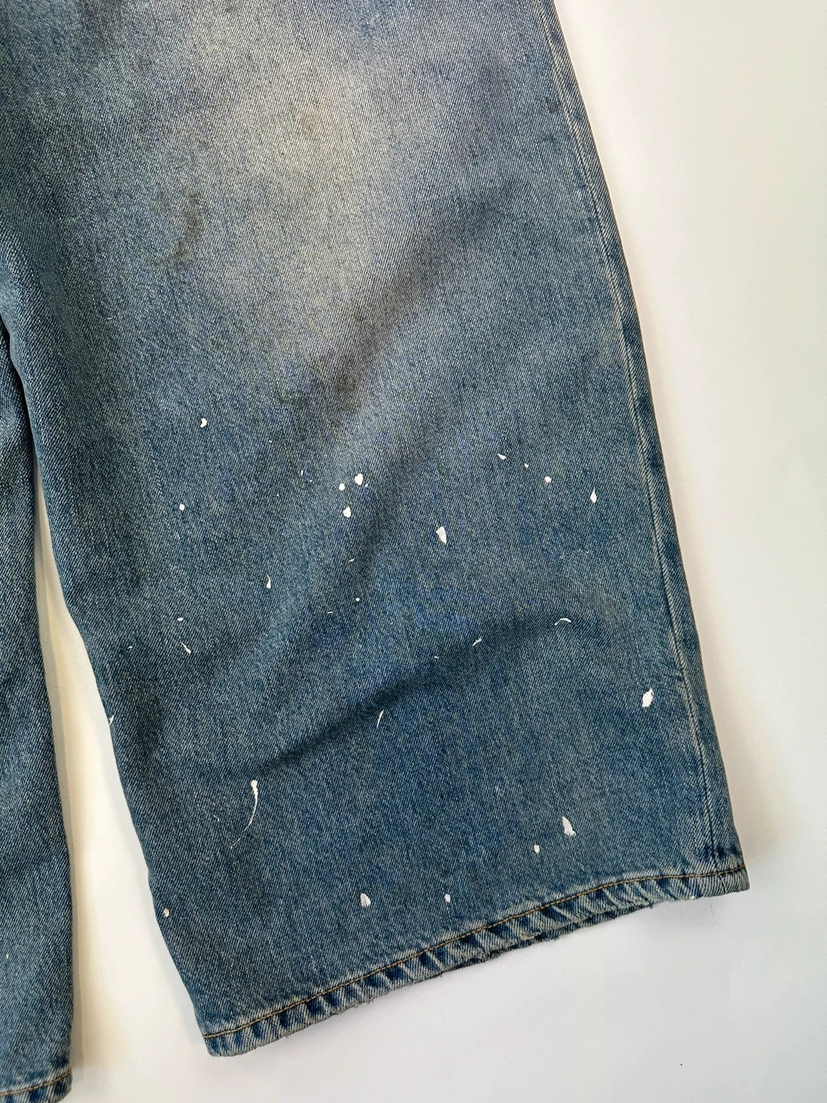 Acne Studios blue and white baggy jeans with intentional paint splatters and non-stretch denim.