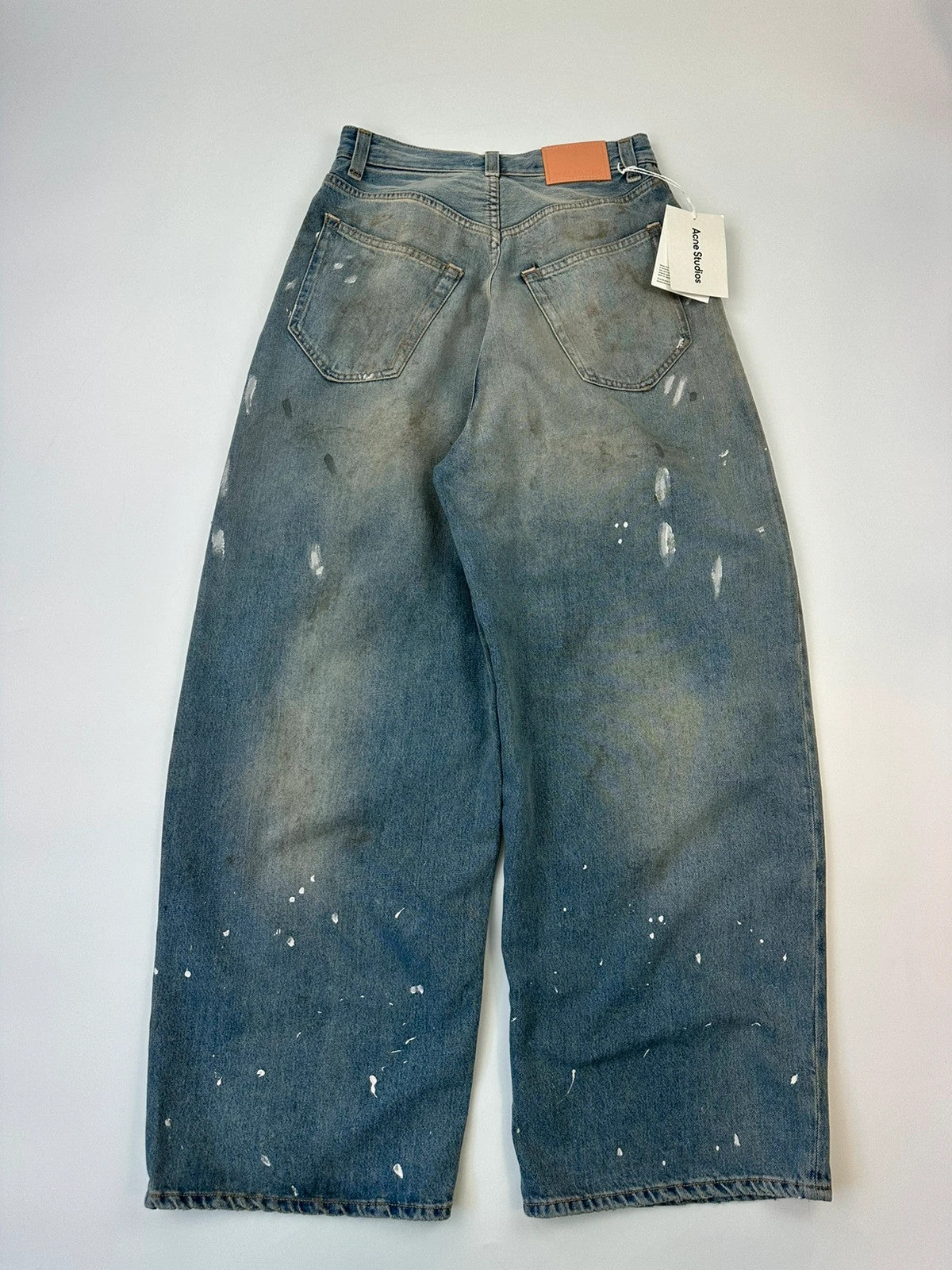 Acne Studios blue and white baggy jeans with intentional paint splatters and non-stretch denim.