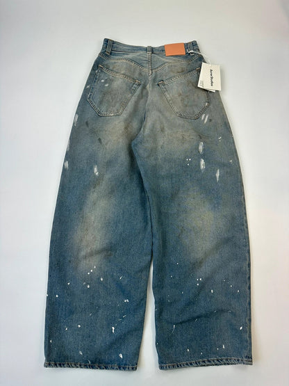 Acne Studios blue and white baggy jeans with intentional paint splatters and non-stretch denim.
