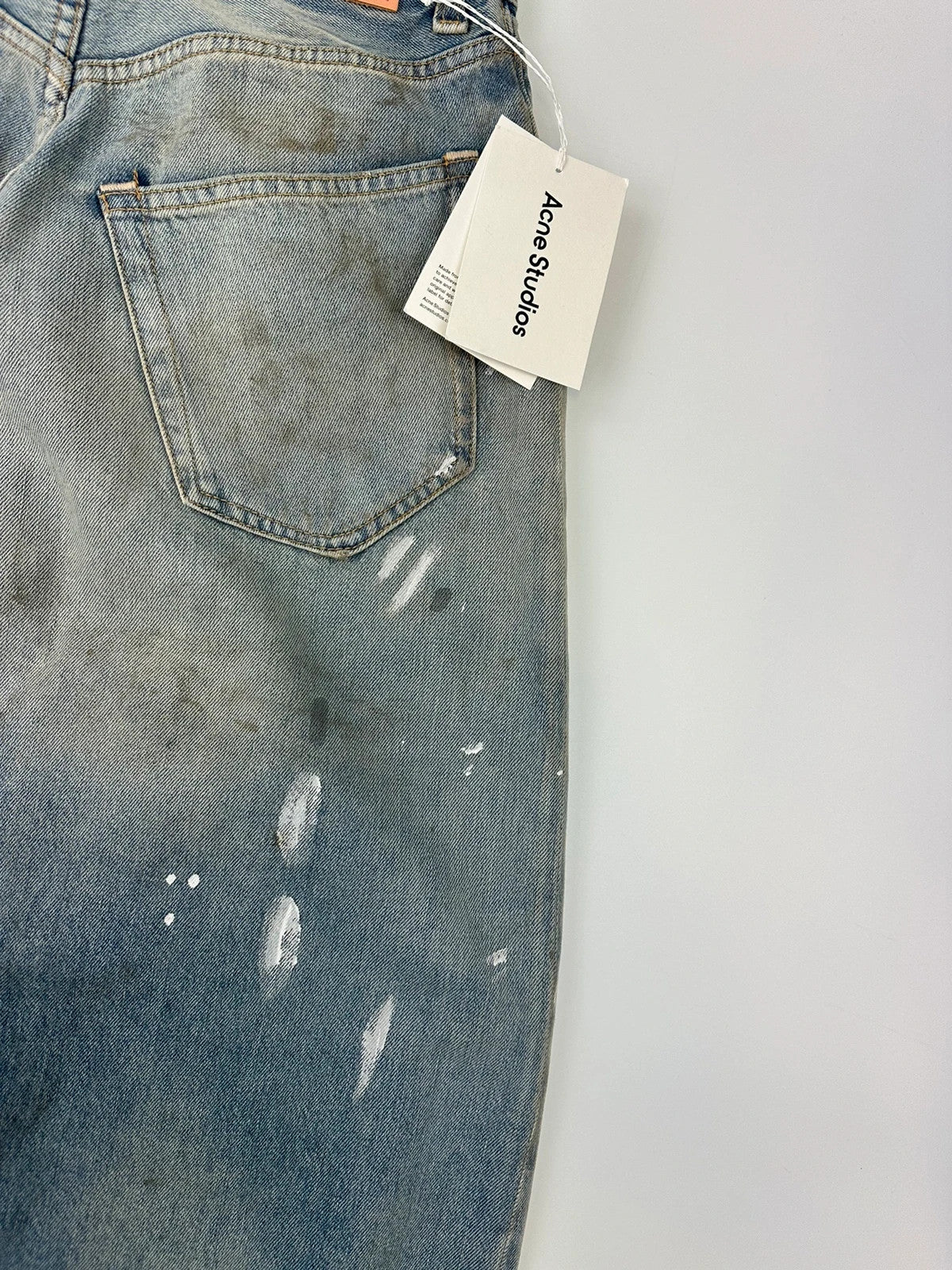 Acne Studios blue and white baggy jeans with intentional paint splatters and non-stretch denim.