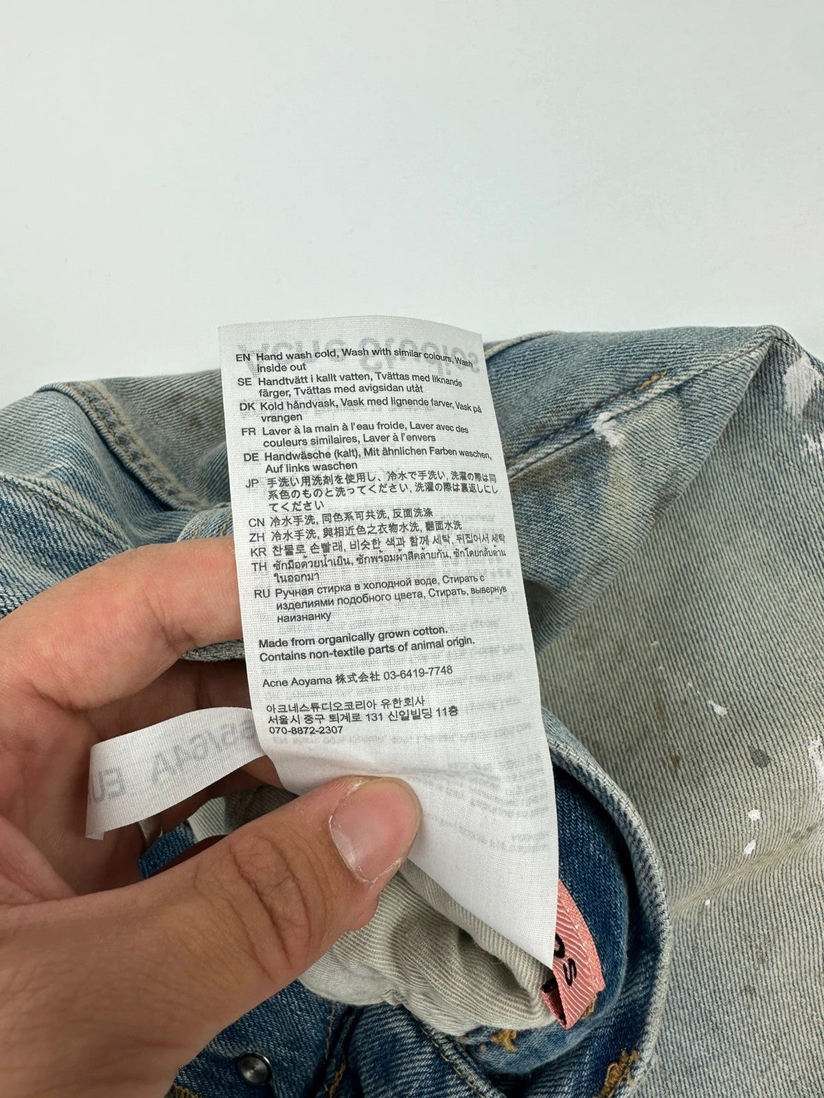 Acne Studios blue and white baggy jeans with intentional paint splatters and non-stretch denim.